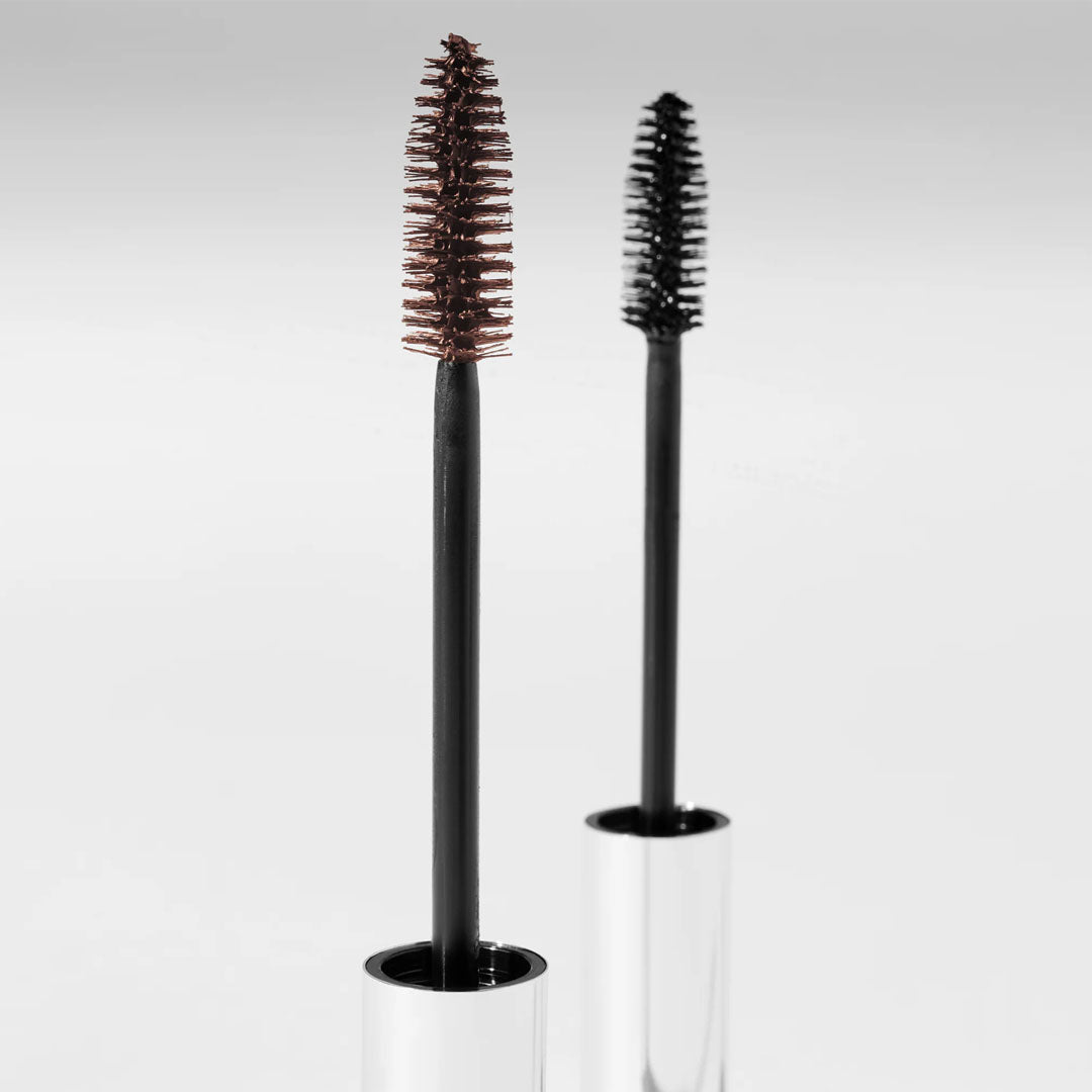 Two Total Lash Serum Mascara wands with brown and black tapered bristle brushes against a light gray background.