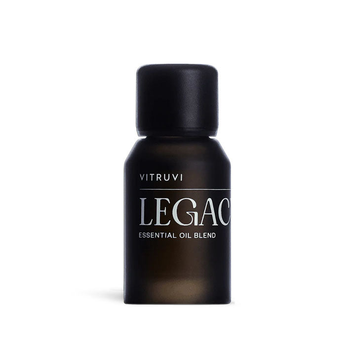 Small, dark brown Vitruvi Legacy essential oil blend bottle with a black cap on a white background.